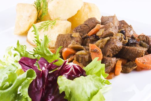 Meal of stewed beef steak with roast potatoes and fresh salad