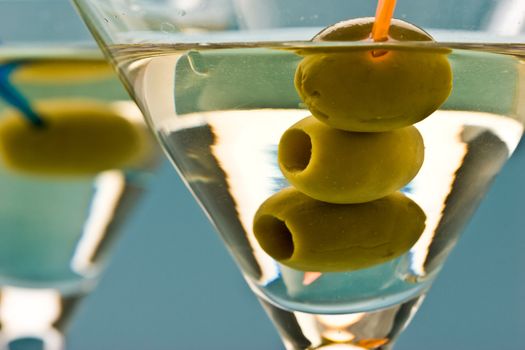 two bocal of martini with olive over blue