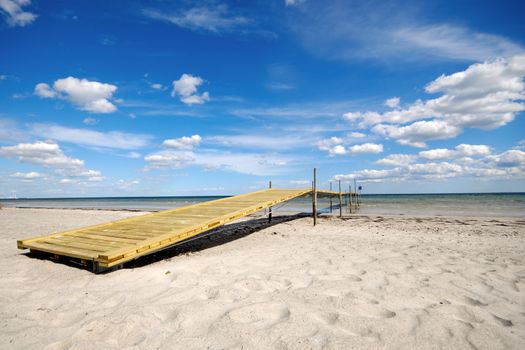 Bridge on beach. The sky is blue with clouds.