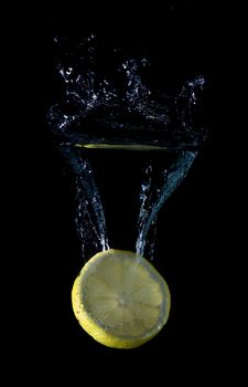 Lemon splashing on a water surface with a black background.