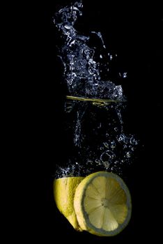 Lemon splashing on a water surface with a black background.