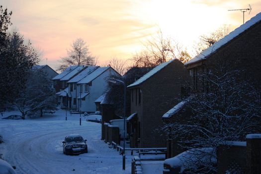 A sunset over a snowy, wintry street