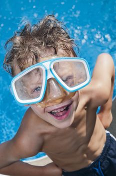 Young boy with attitude showing his muscles and wearig swiming googles