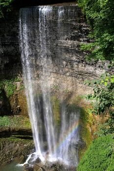 Waterfall in sun with small rainbow