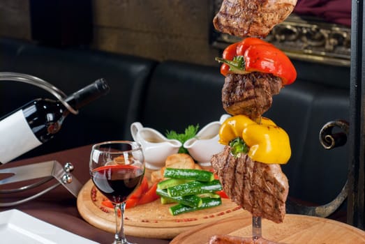 Big tasty roasted meat cuts at skewer on a decorated table