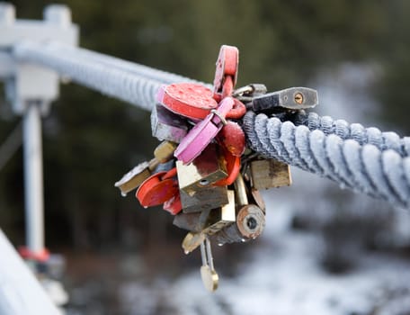 Symbolic locks on the railing of the bridge in frosty steel cable