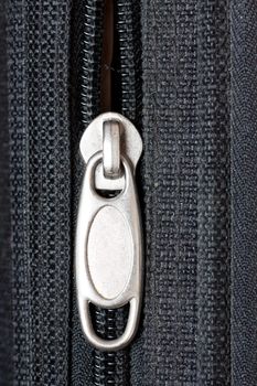 Close-up of a half-opened zipper on a black bag.