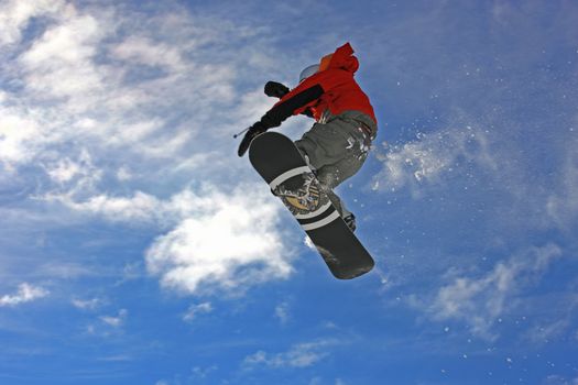 Young snowboarder jumping high over the mountains