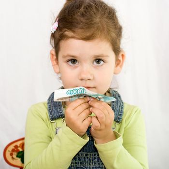 little girl looking directly at camera and holding toy plane, made of money