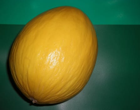 entire yellow honeydew melon on a green background, rock melon. - "cucumis melo inodorus"