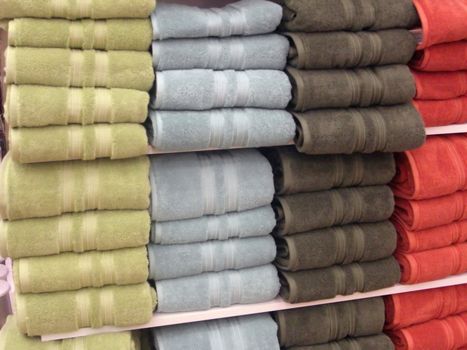 Rows of colorful towels are neatly packed on the shelves.