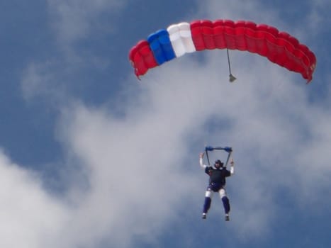 A sky diver is up in the air, and he is slowly preparing to land.