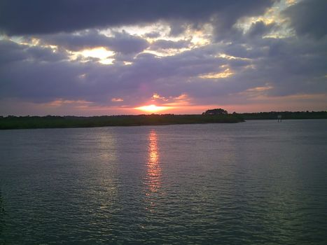 A serene reflection of the sky is sprawled in a very calm lake as the sun gradually prepares to call it a day.