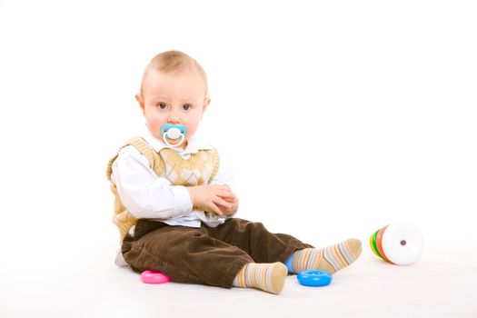small boy with pacifier plays on the floor