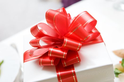 a white present box tied up by a red bow
