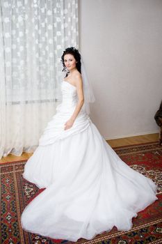 a beatiful bride in a long white dress by the window