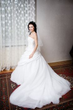 a beatiful bride in a long white dress by the window