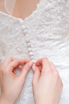 hands of girls help to the bride to button a wedding dress
