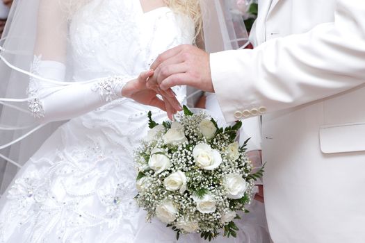 a groom puts on a wedding ring to the finger of the bride