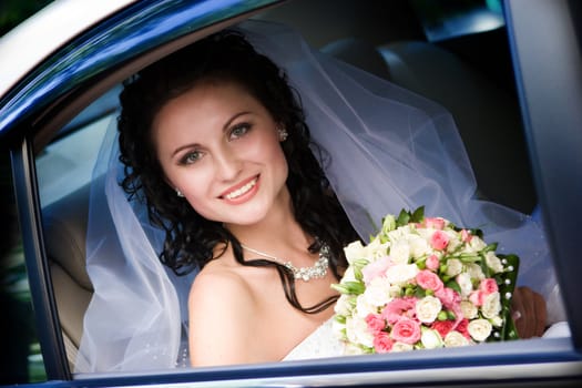 Portrait of the smiling bride sitting in the car
