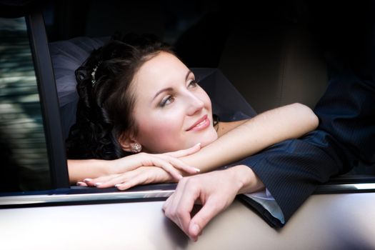 Portrait of the smiling bride sitting in the car