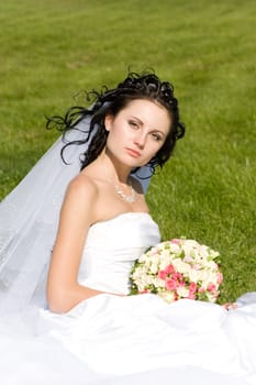 beautiful bride with a flower bouquet on the green grass