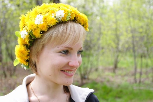 smiling girl with a wreath from dandelions