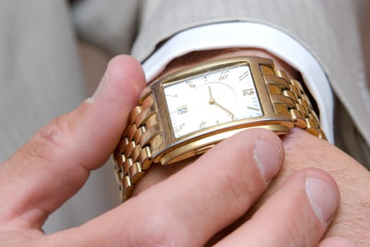 a golden watch on the hand of a man in a light suit