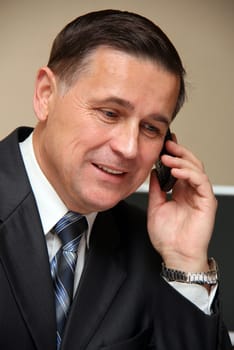 The man in suit talking on a mobile phone