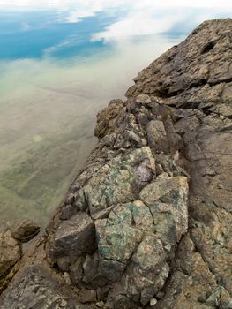 Mineral rich geologic formation of rock at water's edge.