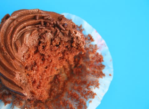 Chocolate cupcake decorated with icing which has a bite missing