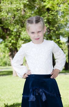 The portrait of the girl in park, becomes angry and has rested hands against a waist