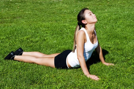 young woman is engaged in yoga, in summer on a green grass