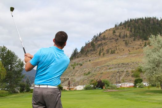 Young golfer following his shot from the fairway to green