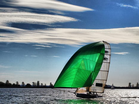A boat with a green spinnaker sailing on Draycote Water
