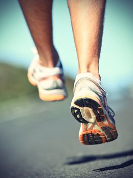 Running shoes on runner - closeup of sport shoes outdoors on man runner during run.