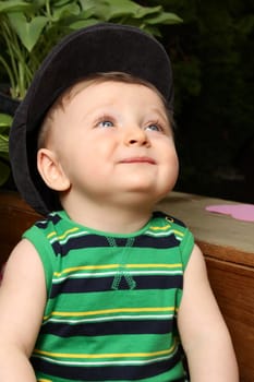 Cute baby boy wearing a hat sitting outside