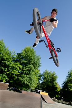 Bmx rider performing a tail whip at a quater pipe ramp on a skatepark.