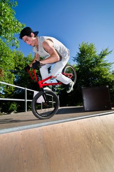 Bmx stunt performed at the top of a quarter piper ramp on a skatepark.