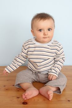 Cute baby boy wearing a striped shirt against blue background