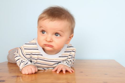 Cute baby boy wearing a striped shirt against blue background