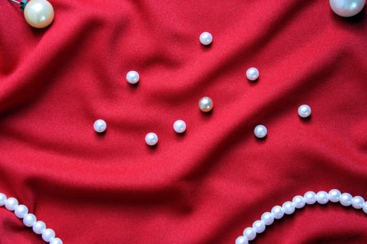 Nacreous pearls and necklace on a red fabric with folds