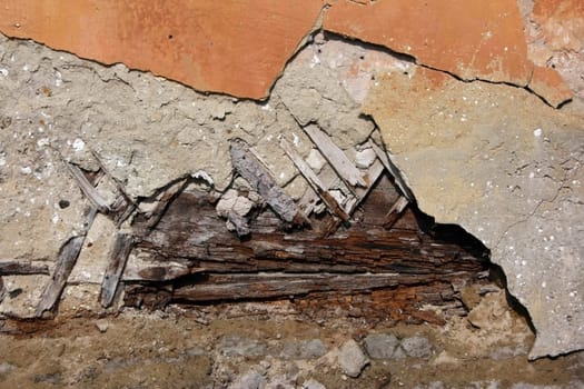 Fragment of an old wall of orange colour with the fallen off plaster
