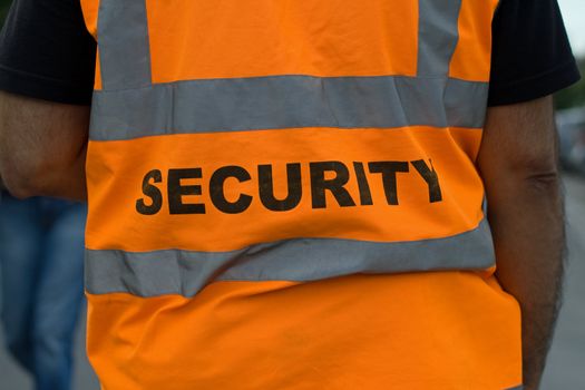 Back of a security guard in orange uniform jacket