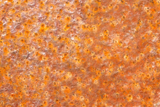 Background of rusty metal with dimpled areas with yellow, red and orange colours.
