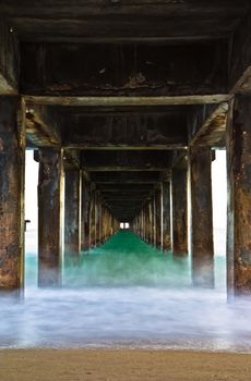 Pillars of the bridge on the beach. At sunset.