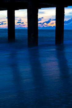 Pillars of the bridge on the beach. At sunset.