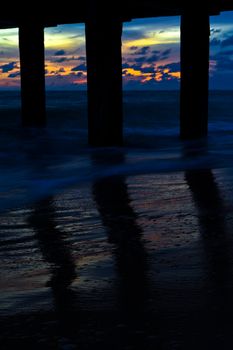 Pillars of the bridge on the beach. At sunset.