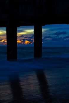 Pillars of the bridge on the beach. At sunset.