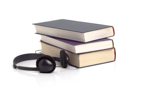 Books and headphones on white background with a faint reflection, suggesting the concept of audio books